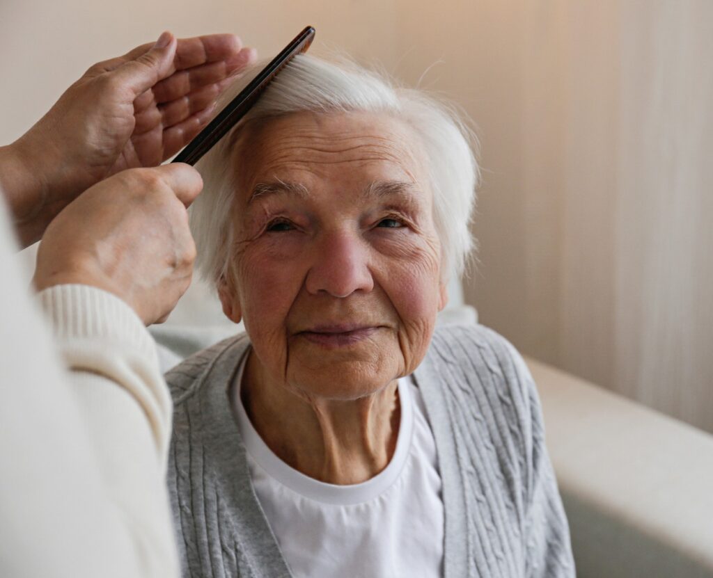 Eine nicht identifizierbare Frau, die einer älteren Dame Fürsorge entgegenbringt, b